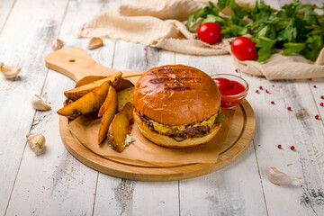 Wall Mural - cheeseburger on the Board with potato wedges and ketchup on white wooden table