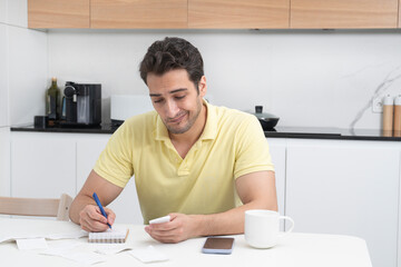 Close up of unhappy man sitting at the table, stressed and confused by calculate expense from invoice or bills, have no money to pay mortgage or loan. High prices and spending money concept