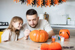 © Julija - Father and daughter making Halloween decorations at home while sitting at wooden table.