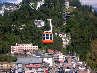 The cable car passing above the houses  vehicles on the road looks mesmerizing at Gangtok in Sikkim. It routes 2 km two-an-from and carries 24 passengers. This is the 1st cable car in Northeast India