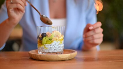 Wall Mural - Woman eating chia pudding with fruits at a restaurant