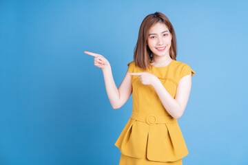 Wall Mural - Portrait of young Asian woman posing on blue background