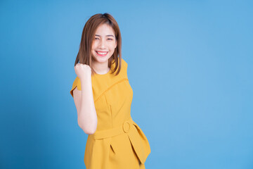 Wall Mural - Portrait of young Asian woman posing on blue background