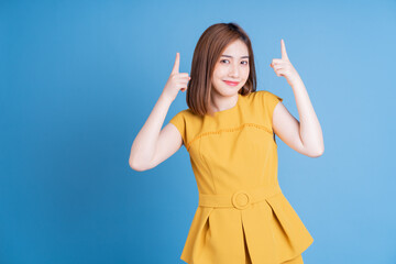 Wall Mural - Portrait of young Asian woman posing on blue background