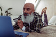 © Caia Image - Mature man with beard and credit card shopping online at laptop