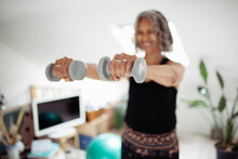 Senior Woman Exercising With Dumbbells At Home