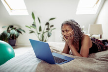 Senior Woman Using Laptop On Bed