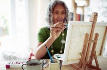 Senior Woman Painting At Small Easel