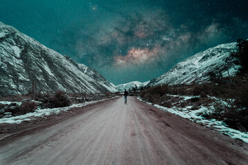 Wall Mural - silhouette of a person walking along a rural road in the middle of the snowy hills at night