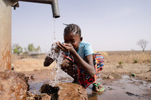 Little African Girl Splashing Herself With Copious Amounts Of Clean Water At A Freshwater Well Located In An Sub Saharan Arid Region