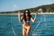 © Syda Productions - people, summer and swimwear concept - happy smiling woman in bikini swimsuit splashing sea water on beach