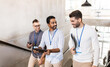 © Syda Productions - business, people and corporate concept - group of men with conference badges, folder, tablet pc computer and smartphone walking up office stairs