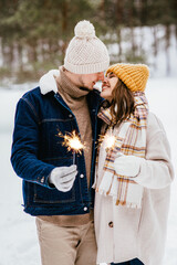 Poster - people, christmas and holidays concept - happy smiling couple with sparklers in winter forest