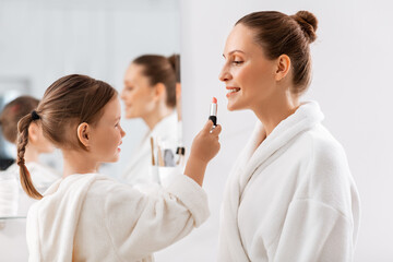 Sticker - beauty, family and people concept - happy smiling mother and little daughter with lipstick applying make up in bathroom