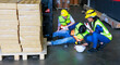 © NVB Stocker - First Aid and safety first. Engineering talking on walki talki radio to employee while his warehouse coworker lying unconscious at industrial factory. Health insurance emergency accident in workplace.