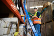 © NVB Stocker - Portrait handsome Asian male warehouse professional worker in safety vest and hardhat helmet in warehouse factory industrial. product in cardboard boxes on stored shelves.