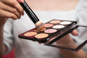 Closeup woman hand while holding the brush and polishing the powder pallet