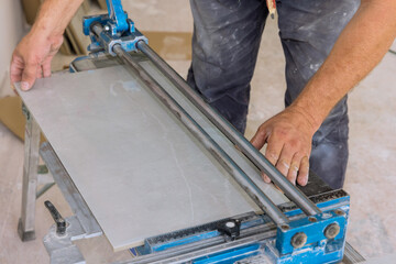 Canvas Print - Using manual tools equipment, a construction worker cuts the ceramic tile using manual tools for laying ceramic tiles in place