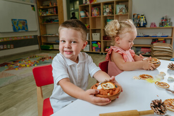 Preschooler boy and girl playing with natural materials in kindergarten or day care centre