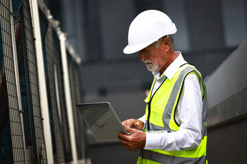 Senior engineer wearing safety vest and helmet working on laptop at construction site line , Chief engineer  design and check the job progress at construction site