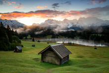 A Scenic View Of Log Cabins Against A Geroldsee Lake And The Karwendel Mountains, Bavaria