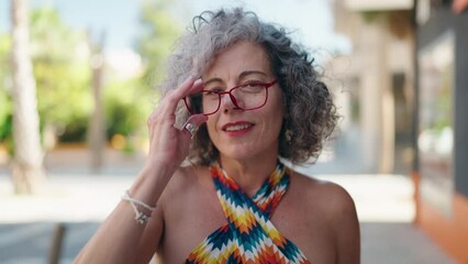 Wall Mural - Middle age grey-haired woman smiling confident wearing glasses at street