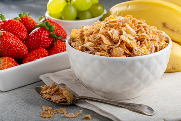 Corn flakes in the bowl with berries on the table.