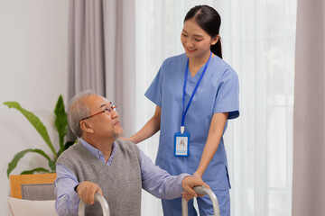 Asian nurse holding an elderly man with a walking stick for physiotherapy.