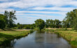 krajobraz rzeki Osobłogi w zachodniej Polsce w jasnych zielono niebieskich barwach i lekko pochmurnej pogodzie