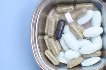 Pharmaceutical medical pills, blister-packaged capsules, and tablets strewn across a blue background.