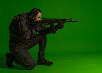 soldier in the studio on a green background with colored light. a man in military uniform with a gun, rifle or machine gun. military. airball player