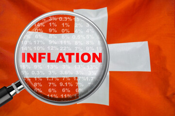 Magnifying glass focused on the word inflation on Switzerland flag background. Hike interest rate. Inflation income crisis. Inflation, tax, cash flow and another financial concept in Swiss