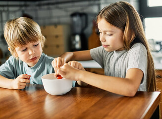 Wall Mural - child girl boy kid brother sister food breakfast strawberry fruit berry fresh diet vitamin health healthy eating kitchen snack morning