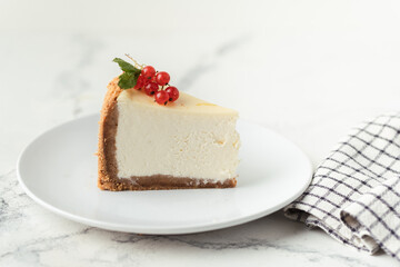 Wall Mural - The piece of Classic New York cheesecake in the white plate decorated with red currant berries on the white background