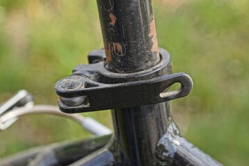 part of a metal tube with an iron clamp and a black plastic handle on a green background