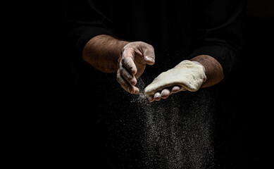 Wall Mural - Beautiful and strong men's hands knead the dough from which they will then make bread, pasta or pizza. A cloud of flour flies around like dust. Food concept