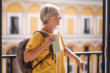 Wall Mural - Happy Caucasian senior tourist woman in yellow jersey and glasses visiting Alcazar, a historic famous place residence in Seville, Spain - travel vacation concept