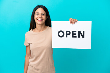 Wall Mural - Young woman over isolated background holding a placard with text OPEN with happy expression