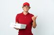 © luismolinero - pizza delivery man over isolated white background pointing to the side to present a product