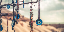 Amulets Against Evil Eye Hanging On Tree In Front Of Sandy Mountain In Cappadocia, Turkey