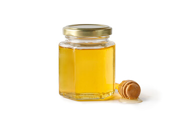 Glass jar of liquid honey with metal lid, wooden honey dipper, drizzler isolated on a white background. Superfood, alternative sugar substitute.