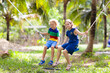 © famveldman - Kids on swing. Playground in tropical resort.