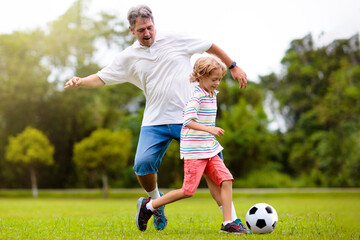 Father and son play football. Dad and kid run.