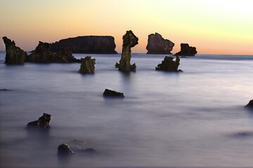 rocks shaped like strange beings that emerge from the sea between silky water