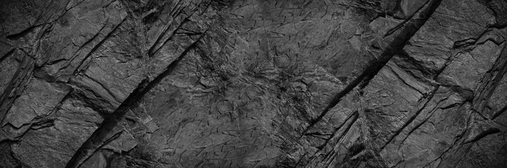 Wall Mural - Black rock texture. Rough mountain surface with cracks. Close-up. Granite stone background with space for design. Web banner. Wide. Panoramic. Dark grey.