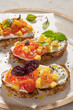 Italian bruschettas with roasted tomatoes, cream cheese, pineapple slices and herbs on a kitchen countertop. Prepared to serve