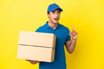 Wall Mural - Delivery man over isolated yellow wall thinking an idea pointing the finger up