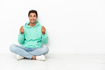 Wall Mural - Caucasian handsome man sitting on the floor making money gesture