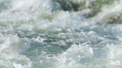 sun shines on rapid river white water waves, closeup abstract detail, slow motion video