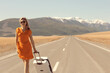 sexy girl in dress with suitcase on the highway, summer travel freedom, woman tourist